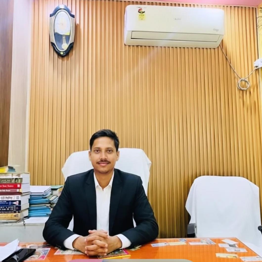 Chandrashiry Tripathi, GST / Tax Consultant, seated at an office desk in a dark suit